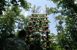 Cadets from the 6th Regiment climb up, unaided and unattached, a high, spaced out wooden ladder. 